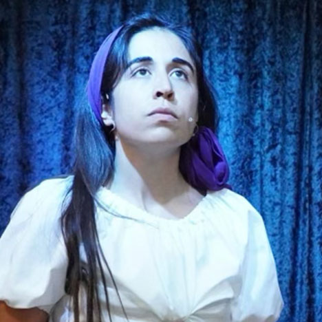A performer in costume looks up into the light